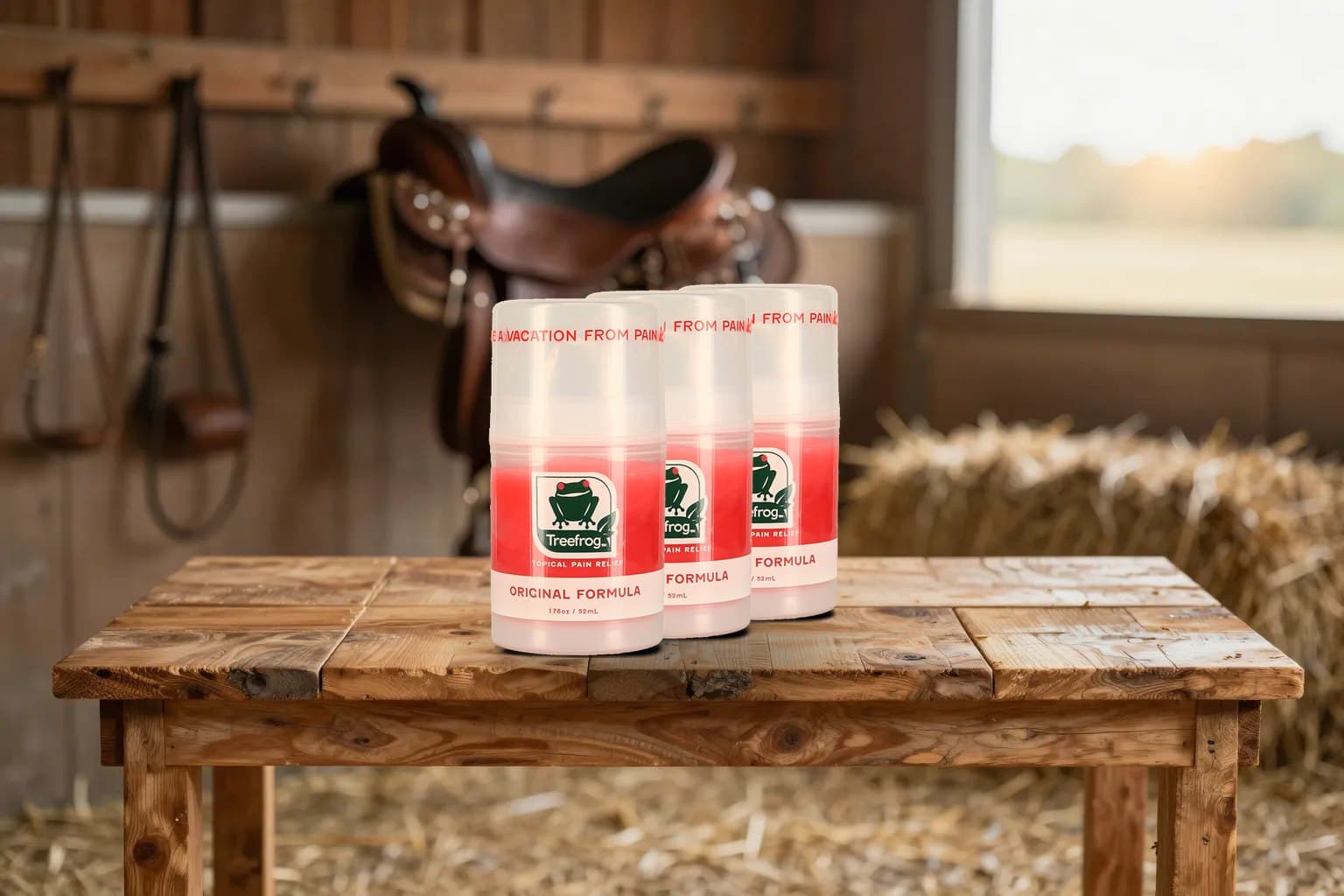 Three Treefrog air pumps on a wooden table in a barn tack room, saddle and hay behind